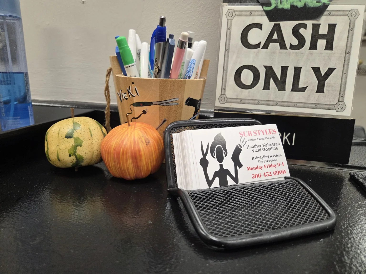 A cash-only sign and SUB Styles business cards on the salon counter.